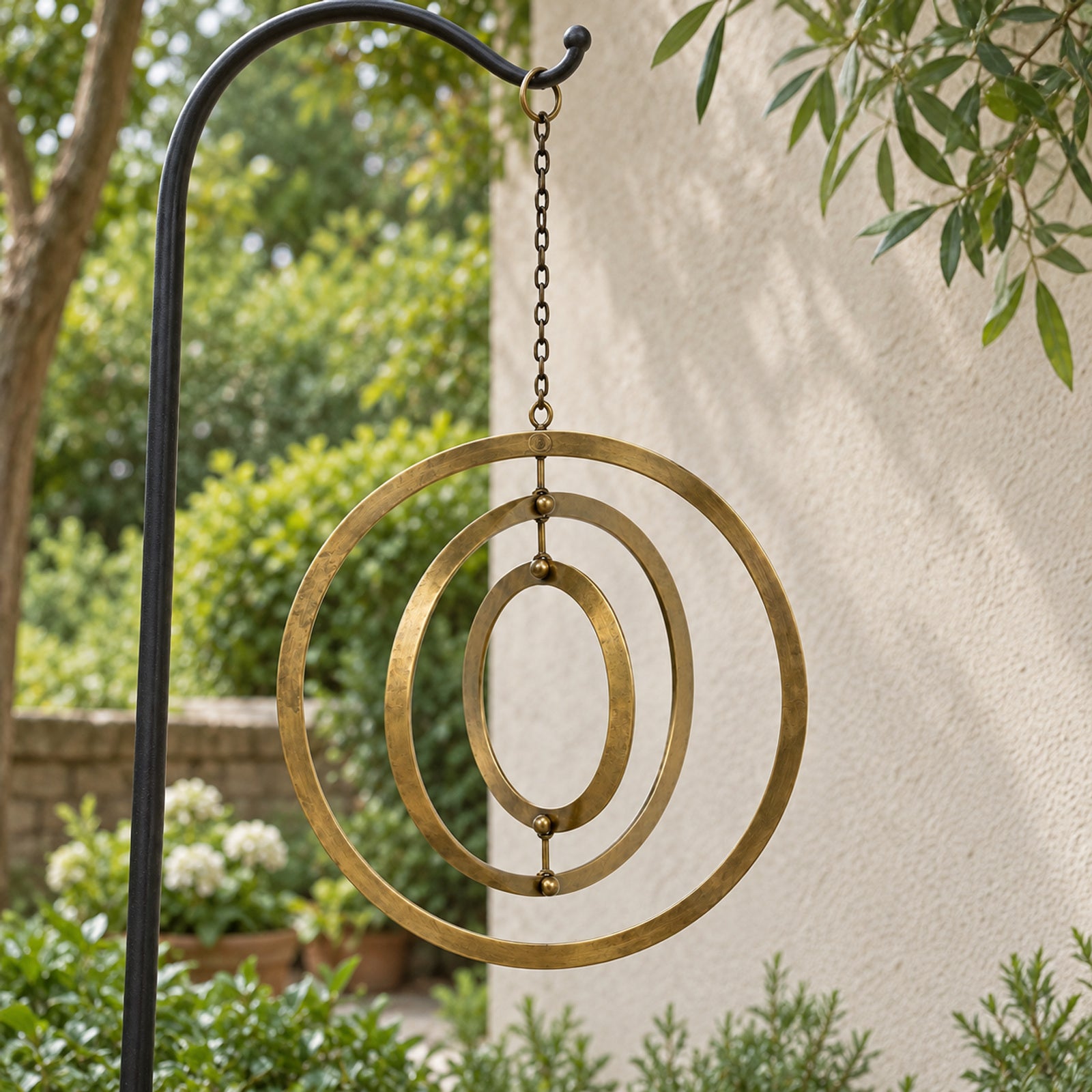 Three linked antique-brass rings hanging in a garden